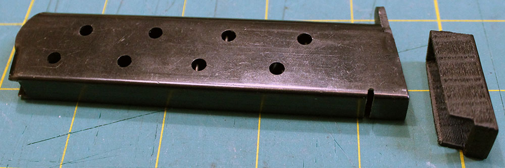 Close-up on the modified magazine, showing a slot cut in the back and an extra plastic part
